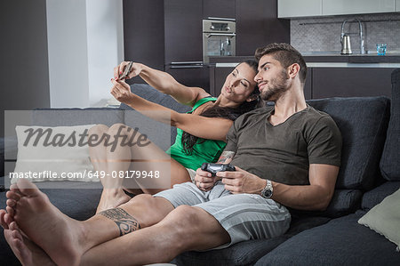 Young couple on sofa taking smartphone selfie