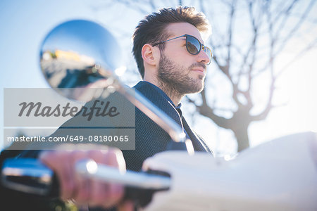 Low angle view of young man on moped