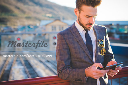 Young man with using digital tablet on railway footbridge