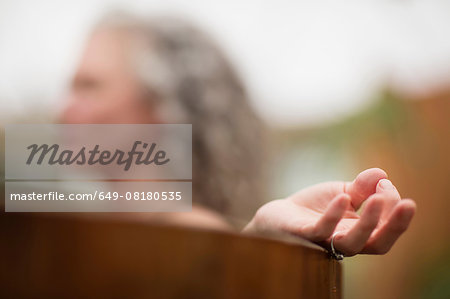 Hand of mature woman meditating in hot tub at eco retreat