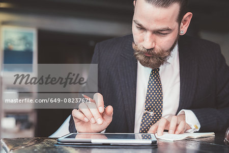 Businessman making diary notes from digital tablet at cafe table