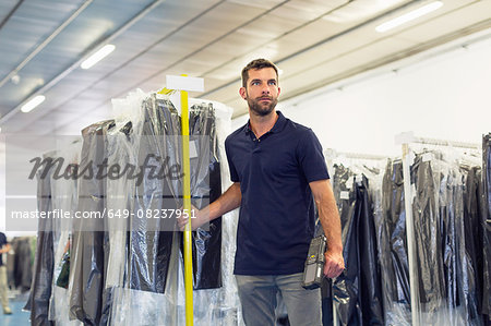 Warehouse worker pulling garment clothes rail in distribution warehouse
