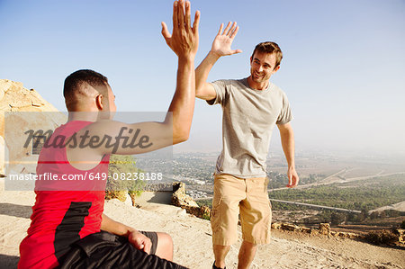 Two male friends, on top of mountain, giving high five