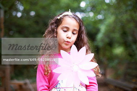 Girl blowing flower pinwheel at garden birthday party