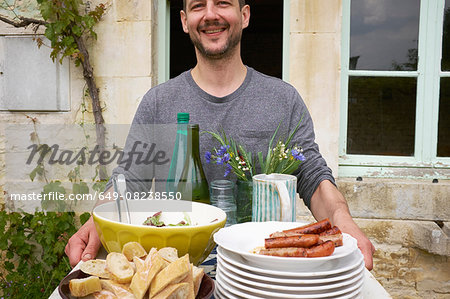 Man carrying tray of food outside house