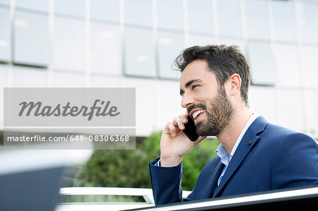 Young businessman talking on smartphone outside office