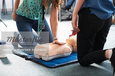 College student performing CPR on mannequin in class