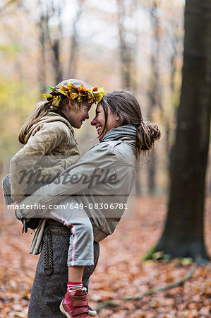 Mother carrying daughter in autumn forest