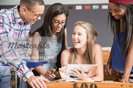 Group of students in classroom, looking at digital tablet
