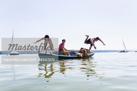 Group of friends diving from boat into lake, Schondorf, Ammersee, Bavaria, Germany