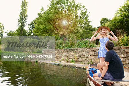 Young woman with boyfriend standing in rowing boat on river