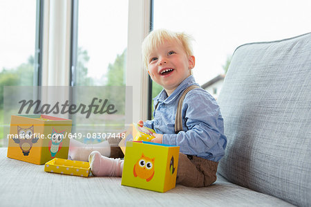 Portrait of happy male toddler playing with building blocks on sofa