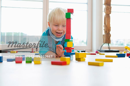 Male toddler playing with building bricks on living room floor