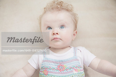 Baby girl lying down, looking away