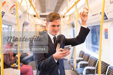 Businessman texting on tube, London Underground, UK