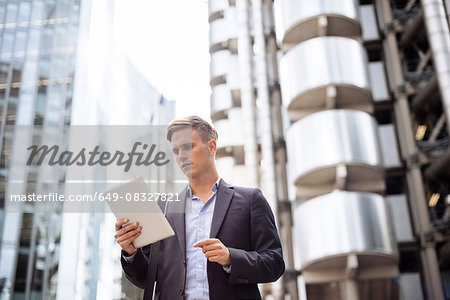 Businessman using digital tablet in street, London, UK