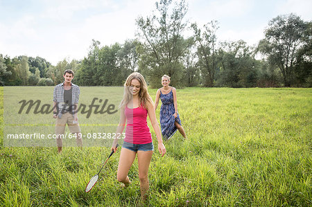 Group of young adults playing badminton in field