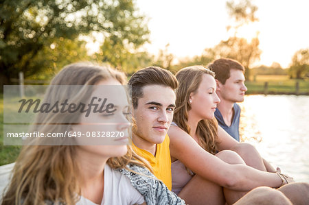 Group of friends sitting by lake, relaxing