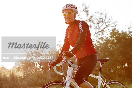 Mature cyclist riding past forest