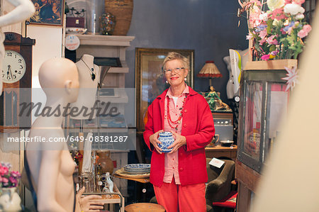 Portrait of mature woman holding china pot in vintage shop