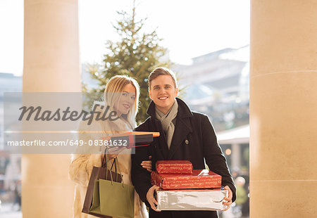 Portrait of young couple carrying xmas gifts in Covent Garden, London, UK