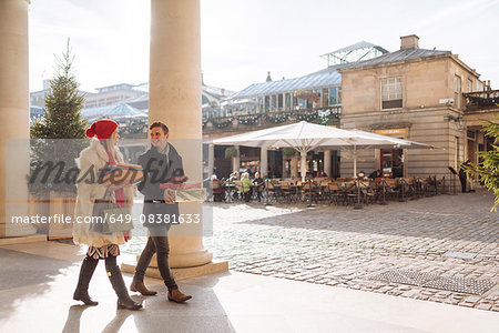 Young couple carrying xmas gifts strolling through Covent Garden, London, UK Young couple carrying xmas gifts strolling through Covent Garden, London, UK