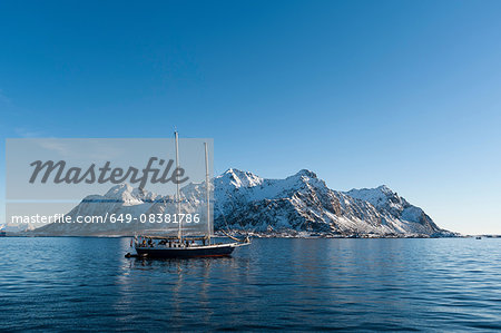 Ship sailing in front of snow capped mountains, Svolvaer, Lofoten Islands, Norway