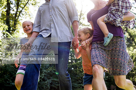 Cropped shot of parents and three young daughters running in park