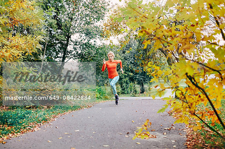 Young female runner running along park path