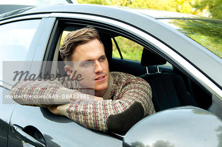 Young man leaning and looking out from car window