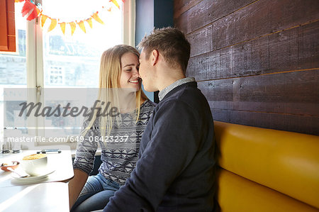 Romantic young couple face to face in cafe window seat