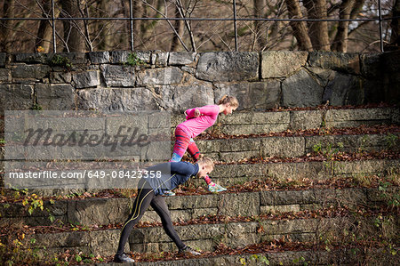 Side view of couple on stone steps bending over, hands behind back stretching