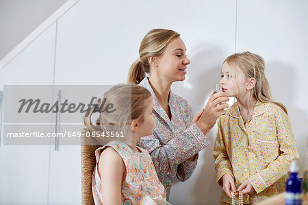 Mother and daughters playing dress-up in bedroom