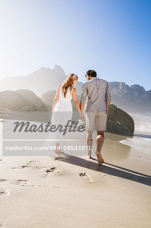 Full length rear view of couple walking on beach holding hands