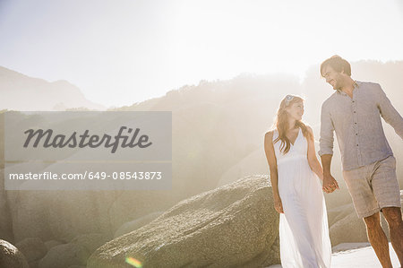 Couple in front of rocks holding hands face to face smiling