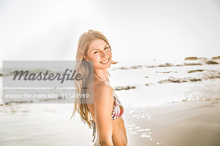 Portrait of woman wearing bikini top looking over her shoulder at beach, Cape Town, South Africa