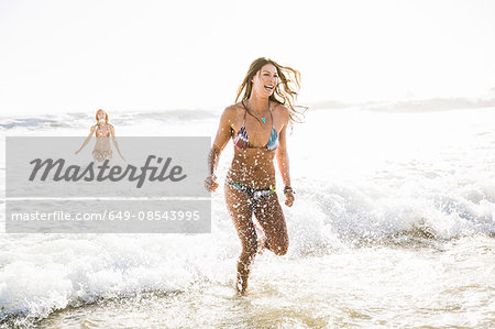 Two women wearing bikini's running in sea, Cape Town, South Africa