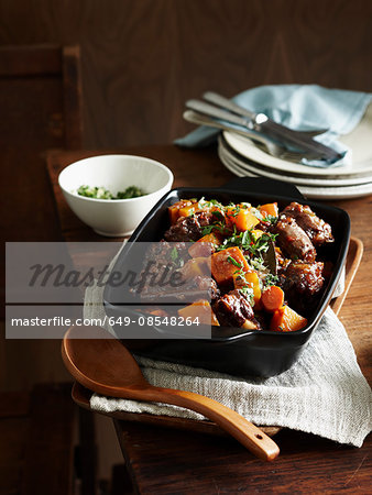 Middle eastern oxtail stew in serving dish with wooden serving spoon