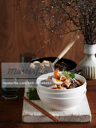 Seafood laksa in stacked bowl on whitewashed cutting board