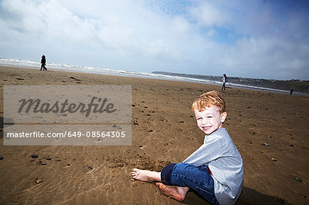 Boy sitting on beach smiling