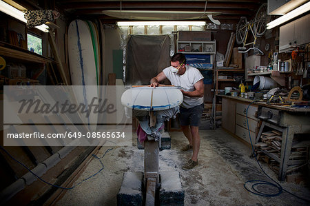 Mature man sanding a surfboard in his workshop