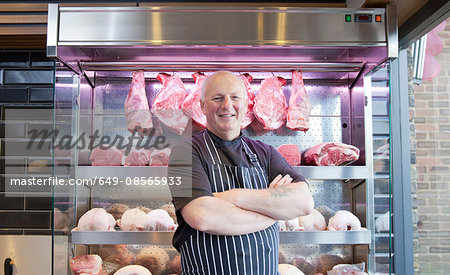 Portrait of butcher with arms folded in butchers shop