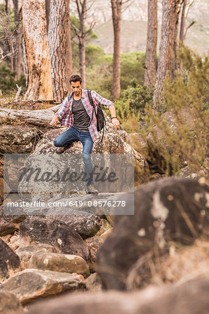 Male hiker hiking down forest rock formation, Deer Park, Cape Town, South Africa