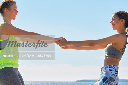 Women wearing sports clothes face to face holding hands smiling
