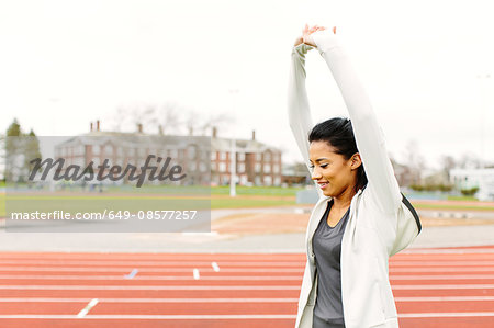 Young woman on running track, stretching