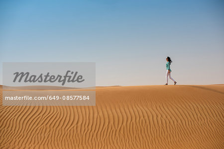 Woman tourist walking on desert dune, Dubai, United Arab Emirates