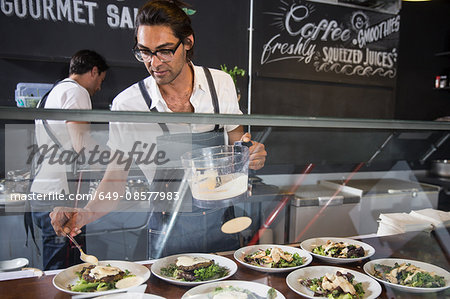 Restaurateurs preparing salad behind service counter