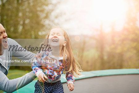 Father and daughter playing on trampoline