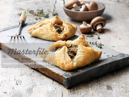 Food, mushroom encroute, vintage board, bowl of raw mushrooms, fresh thyme, rustic wooden table