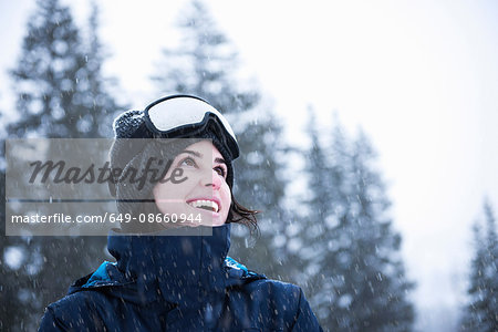 Portrait of young woman wearing ski goggles looking up at snow, Brighton Ski Resort outside of Salt Lake City, Utah, USA